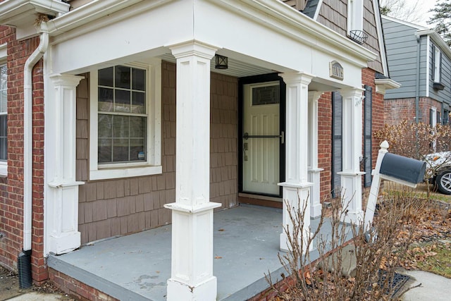 view of exterior entry with covered porch and brick siding