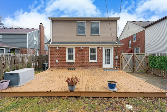 rear view of house with a fenced backyard, a deck, and brick siding