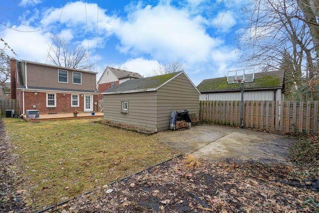 back of house featuring a lawn, fence, an outdoor structure, central air condition unit, and brick siding