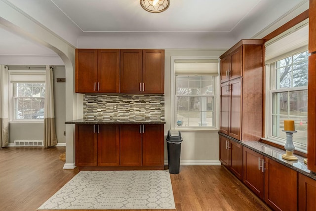 kitchen with dark wood-style floors, dark stone countertops, and visible vents