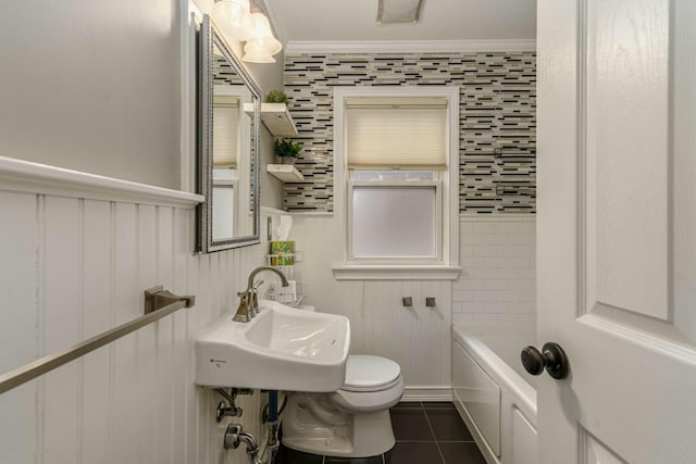 bathroom featuring toilet, ornamental molding, a sink, a tub, and tile patterned floors