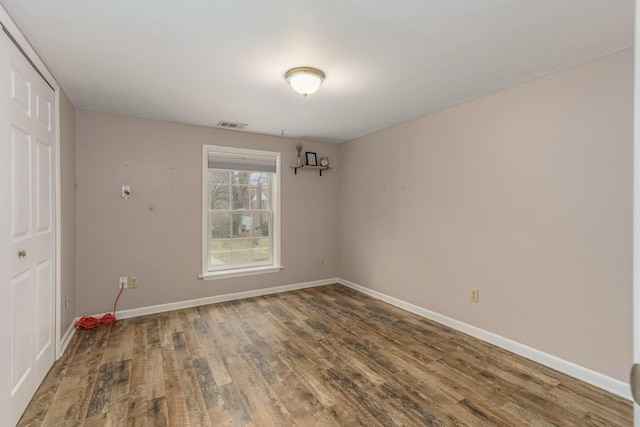 spare room with visible vents, baseboards, and wood finished floors