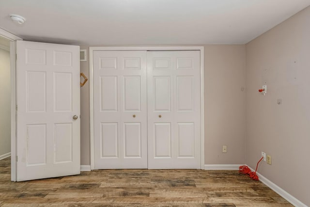 interior space with a closet, visible vents, baseboards, and wood finished floors