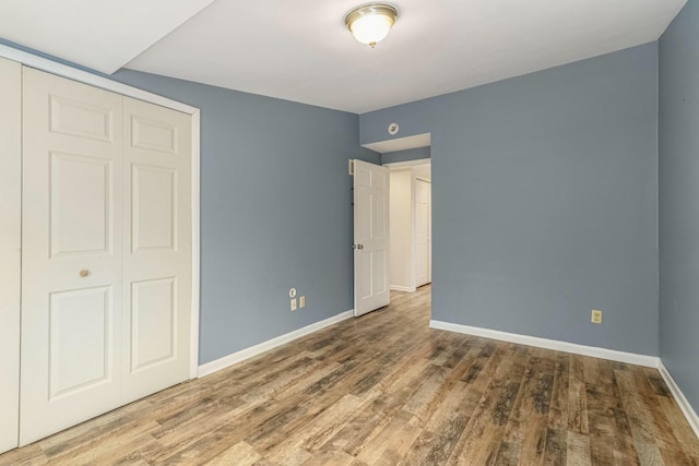 unfurnished bedroom with a closet, baseboards, and wood finished floors