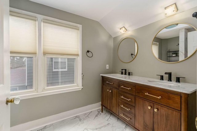 bathroom featuring double vanity, baseboards, marble finish floor, vaulted ceiling, and a sink