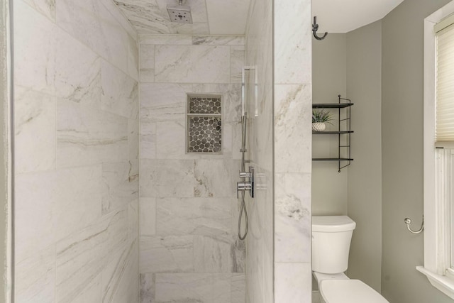 bathroom with a tile shower and toilet