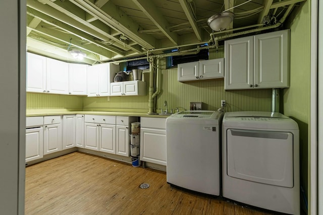 laundry area featuring a sink, washing machine and dryer, cabinet space, and light wood-style floors