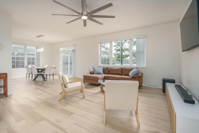 living area featuring baseboards, visible vents, ceiling fan, and light wood finished floors