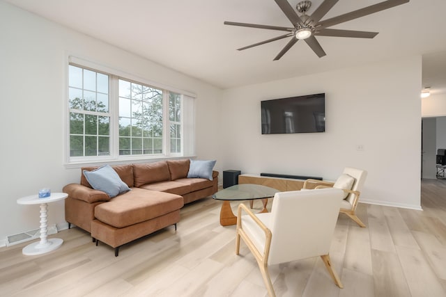 living area with baseboards, visible vents, ceiling fan, and light wood finished floors