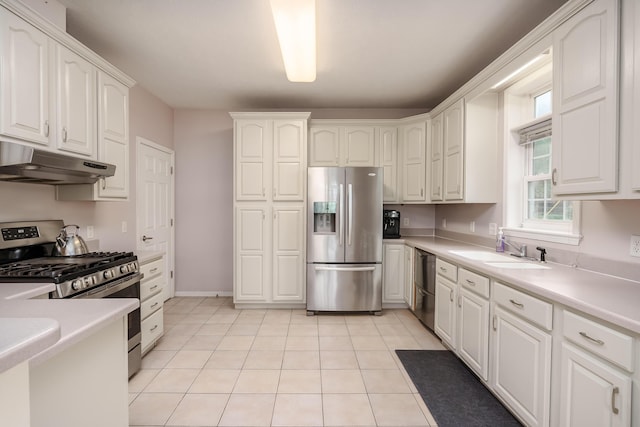 kitchen featuring light tile patterned floors, under cabinet range hood, a sink, white cabinetry, and appliances with stainless steel finishes