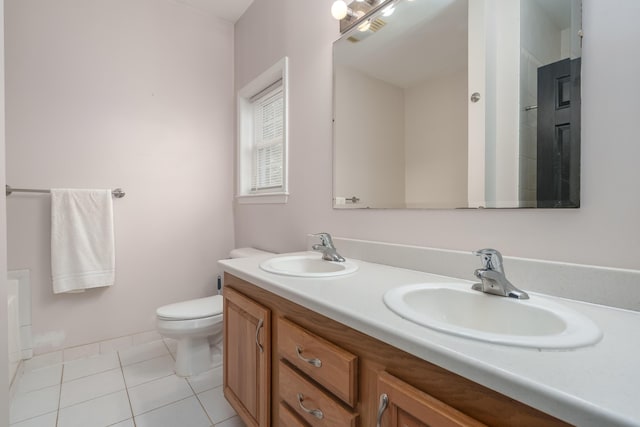 full bath with double vanity, a sink, toilet, and tile patterned floors