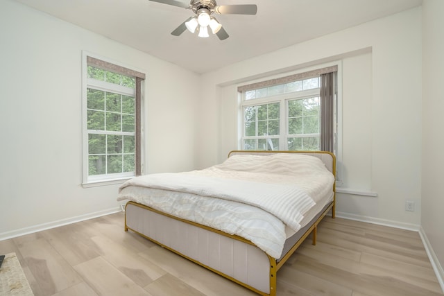 bedroom featuring light wood finished floors, baseboards, and a ceiling fan