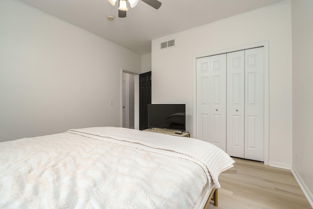 bedroom featuring baseboards, visible vents, a ceiling fan, light wood-type flooring, and a closet