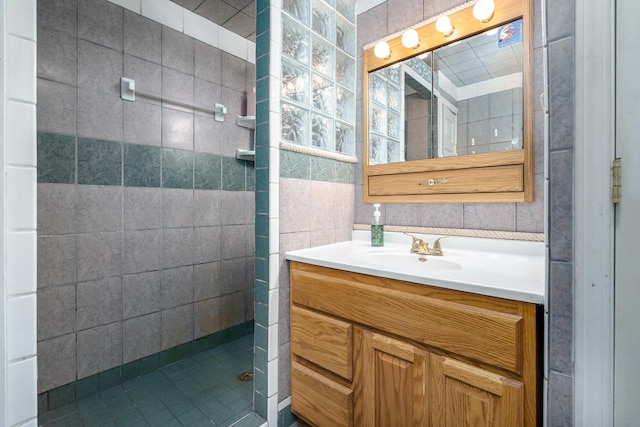 bathroom with vanity, backsplash, a tile shower, and tile walls