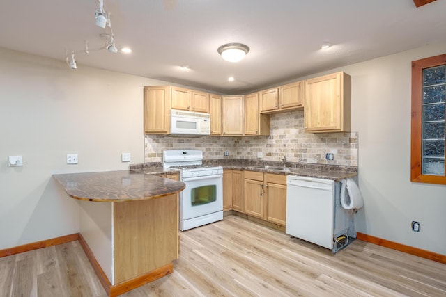 kitchen with a peninsula, white appliances, backsplash, and light brown cabinets