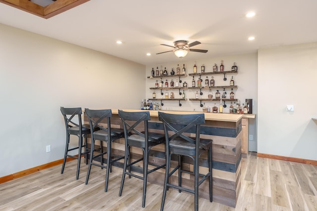 bar with a dry bar, baseboards, a ceiling fan, light wood-style floors, and recessed lighting