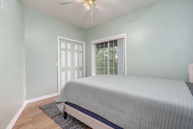 bedroom with a closet, wood finished floors, a ceiling fan, and baseboards