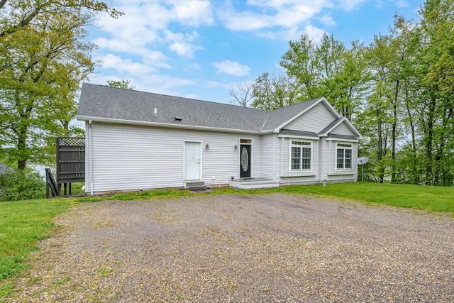 single story home with a shingled roof, a front yard, and driveway