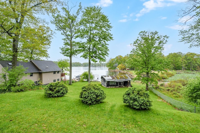 view of yard featuring an outbuilding, a water view, and fence