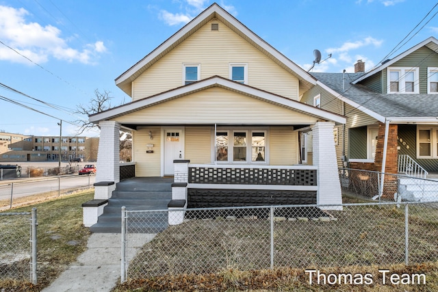 view of front of house featuring a fenced front yard, covered porch, and roof with shingles