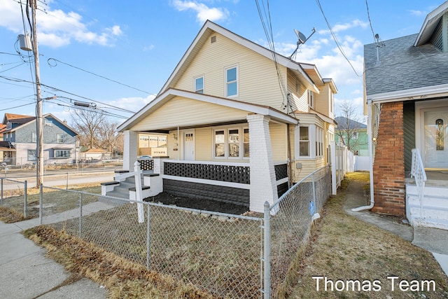 view of side of home featuring a porch and a fenced front yard