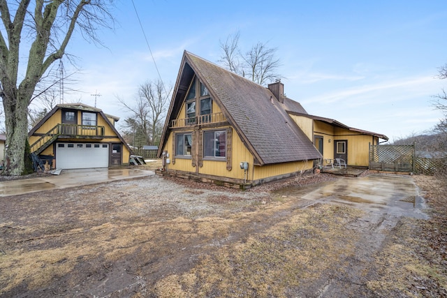 a-frame home featuring a shingled roof, driveway, and a chimney