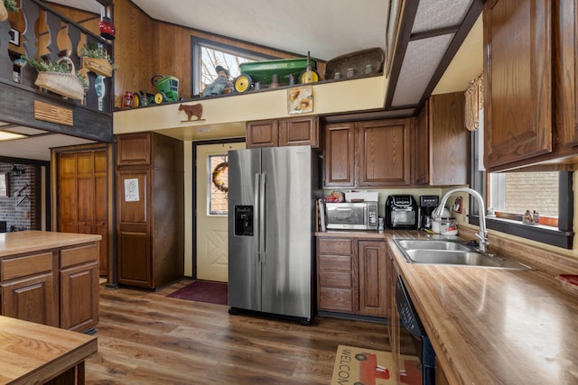 kitchen featuring dark wood-style floors, butcher block countertops, brown cabinets, stainless steel appliances, and a sink