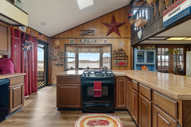 kitchen featuring lofted ceiling, black appliances, plenty of natural light, and wood finished floors