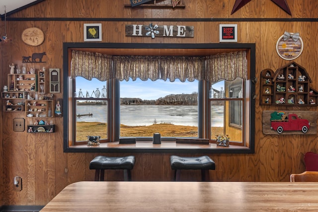 dining room featuring wooden walls and vaulted ceiling