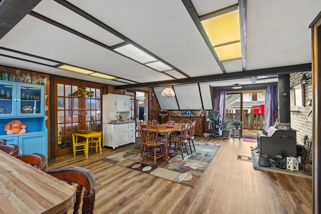 dining space with a wood stove, wood finished floors, and french doors