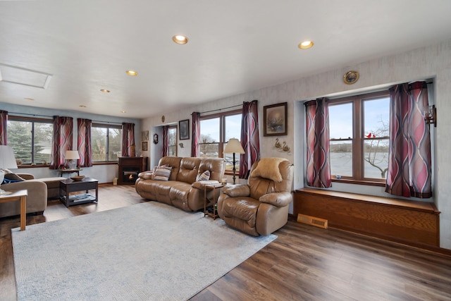 living area with recessed lighting, visible vents, a fireplace, and wood finished floors