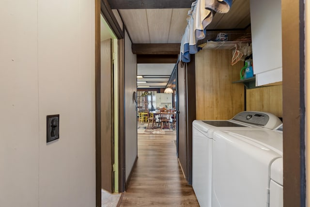 laundry area with independent washer and dryer, cabinet space, and light wood-style flooring