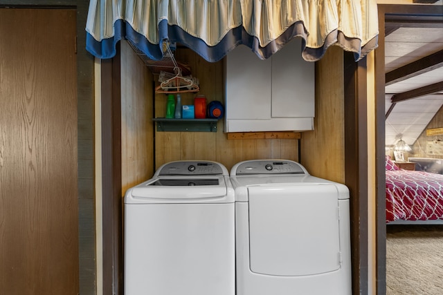 laundry area with carpet floors, washing machine and dryer, cabinet space, and wooden walls