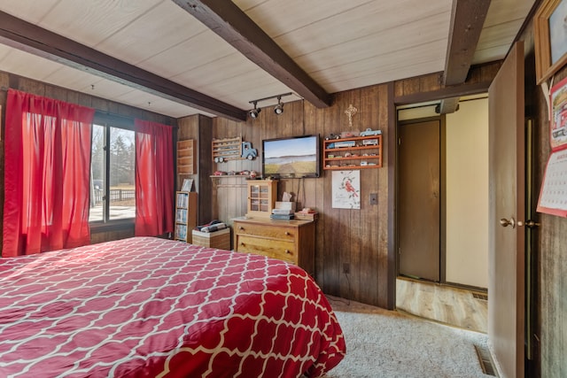 unfurnished bedroom with visible vents, rail lighting, beam ceiling, and wooden walls