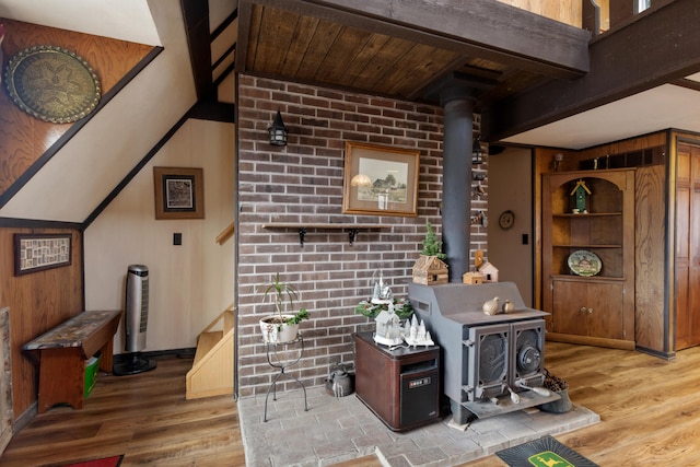 interior space featuring brick wall, wood finished floors, a wood stove, and wooden walls