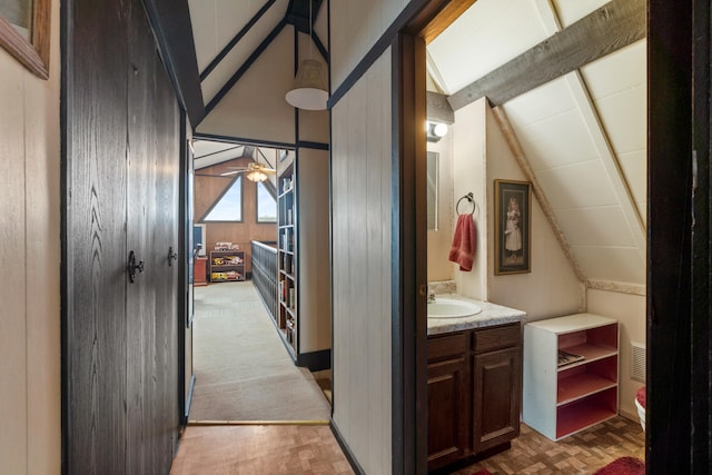 hallway with vaulted ceiling with beams, parquet floors, and a sink