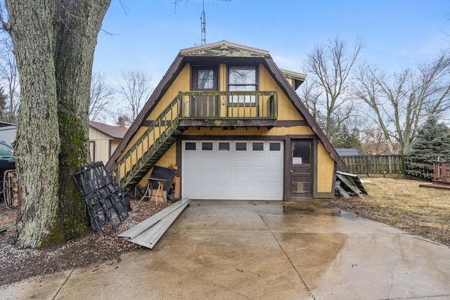 a-frame home with a garage, concrete driveway, fence, and stairway