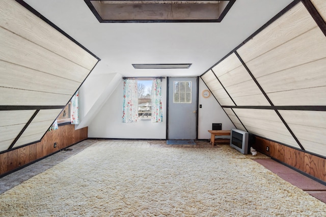 additional living space with wood walls, vaulted ceiling, and carpet flooring