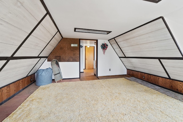 bonus room featuring lofted ceiling, carpet floors, and wooden walls