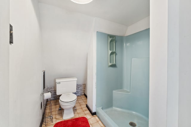 bathroom featuring toilet, a shower stall, and tile patterned floors