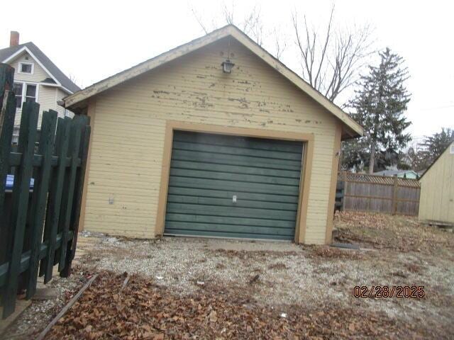 detached garage featuring driveway and fence