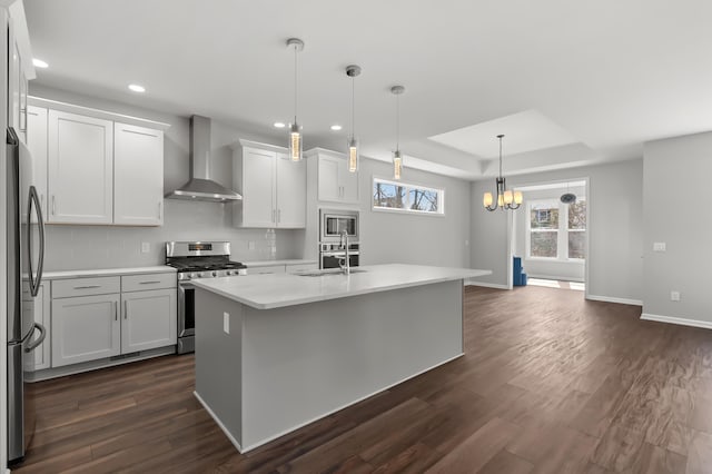 4030 Hollow Wood Dr, Portage, MI 49024 - kitchen with light countertops, appliances with stainless steel finishes, a sink, a tray ceiling, and wall chimney range hood