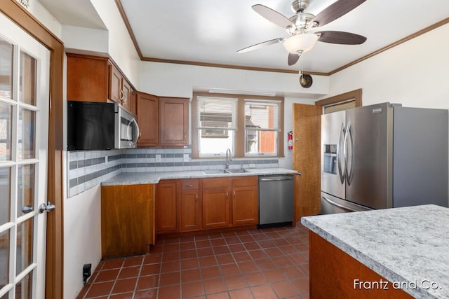 kitchen with tasteful backsplash, light countertops, appliances with stainless steel finishes, brown cabinetry, and a sink