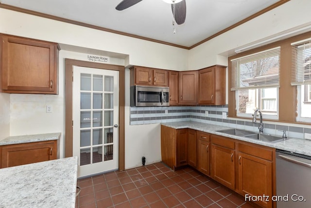 kitchen with brown cabinetry, ornamental molding, decorative backsplash, a sink, and appliances with stainless steel finishes