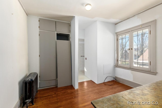 bedroom featuring a closet, radiator heating unit, and wood finished floors