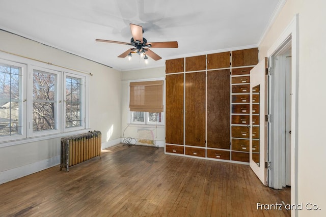 unfurnished bedroom featuring baseboards, radiator, ornamental molding, and hardwood / wood-style flooring