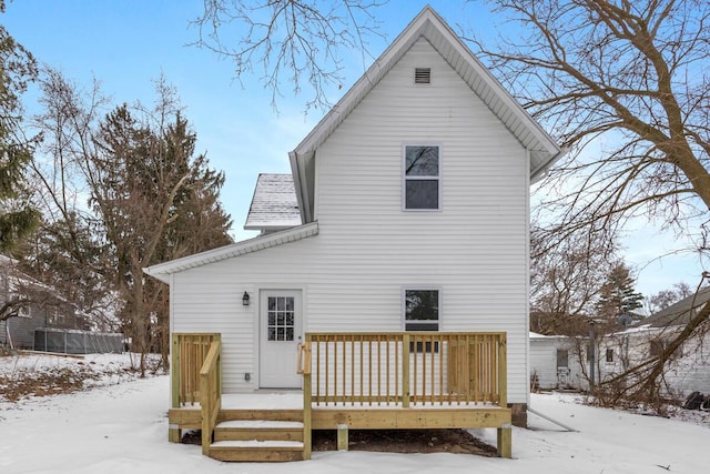 snow covered rear of property with roof with shingles and a deck