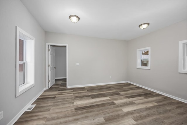 spare room featuring visible vents, baseboards, and wood finished floors