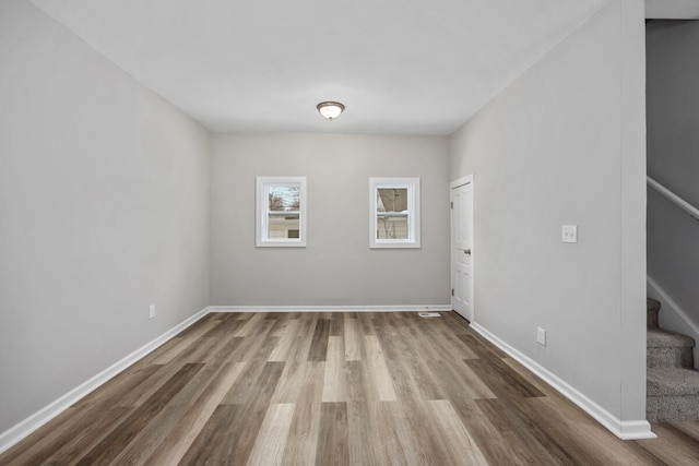 spare room with stairs, wood finished floors, and baseboards