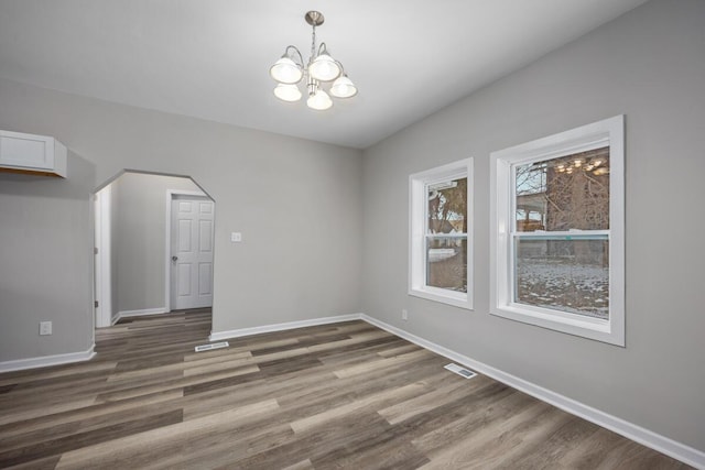 interior space featuring an inviting chandelier, baseboards, visible vents, and wood finished floors